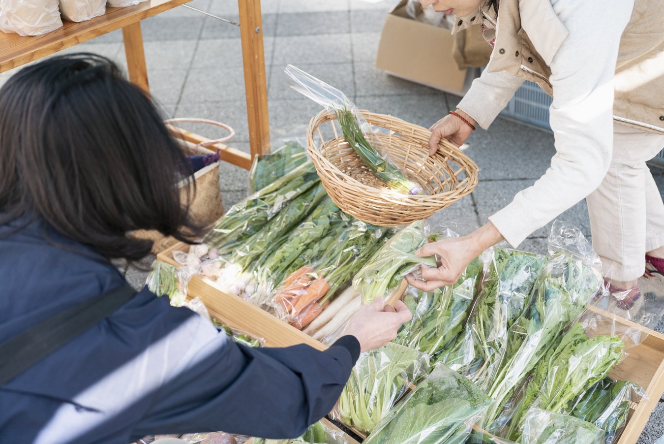 マーケットで地元の野菜を選ぶ来場者と出店者